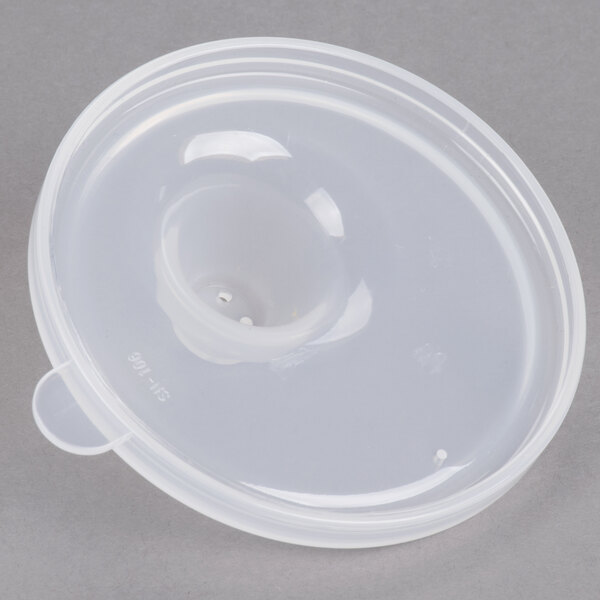 A close-up of a clear plastic lid with a hole over a white plastic bowl.