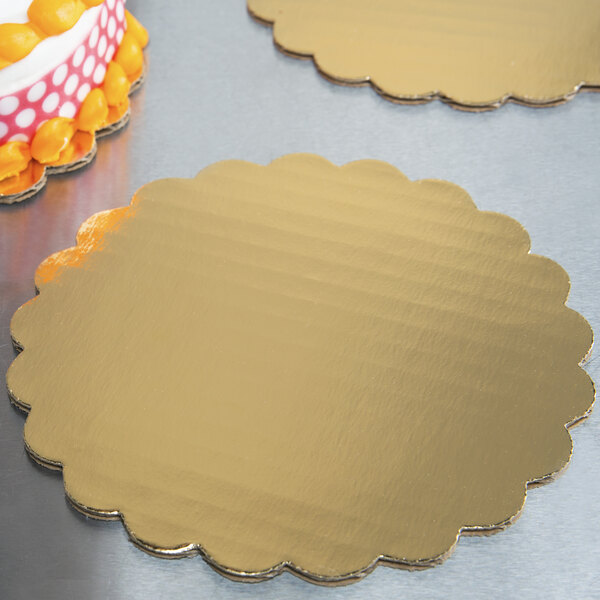 A gold laminated corrugated cake circle with a cake on top.