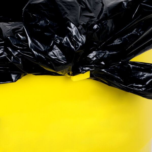 A black plastic bag on a yellow Continental Huskee trash can.