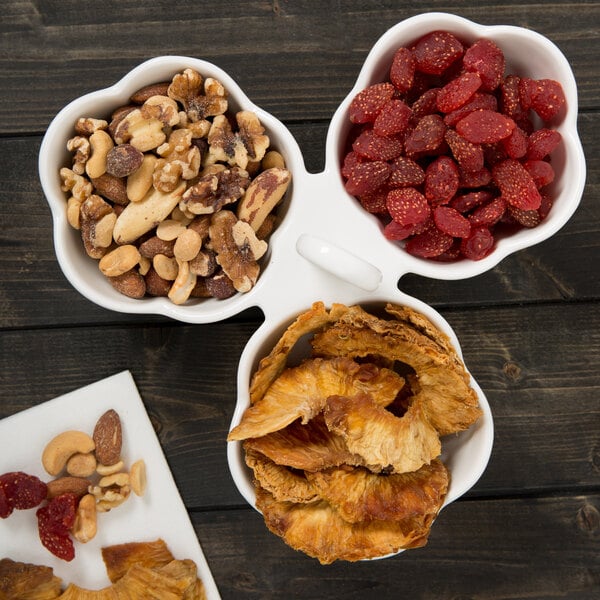 A 10 Strawberry Street white porcelain bowl caddy with 3 bowls of mixed nuts and dried fruit.