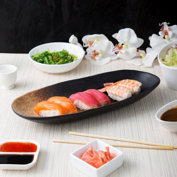 A 10 Strawberry Street Whittier Nagoya oval stoneware platter holding sushi on a table.