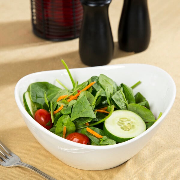 A white porcelain bowl filled with salad and vegetables with a fork.