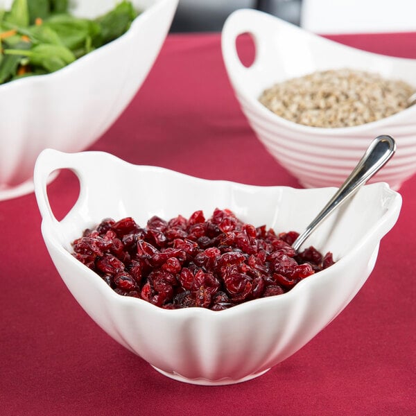 A white porcelain boat bowl with wave texture filled with cranberry sauce and a spoon.