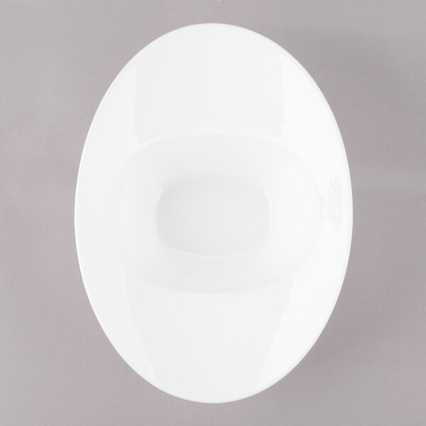 A white oval porcelain bowl with a rim on a gray surface.