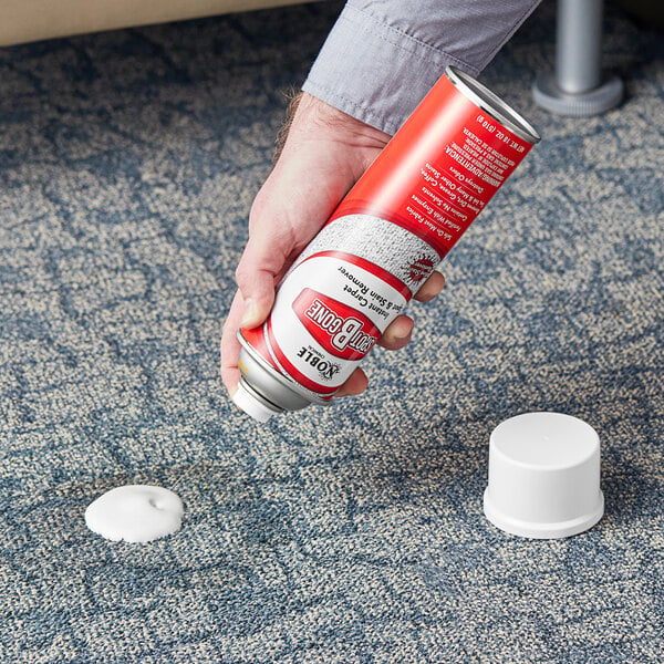 A person using Noble Chemical Spot-B-Gone carpet cleaner to spray a carpet.