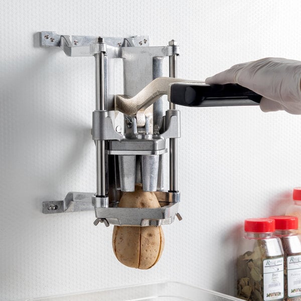 A person using a Nemco Easy FryKutter to cut potatoes.