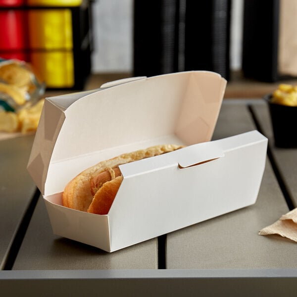 A hot dog in a white paper clamshell container.