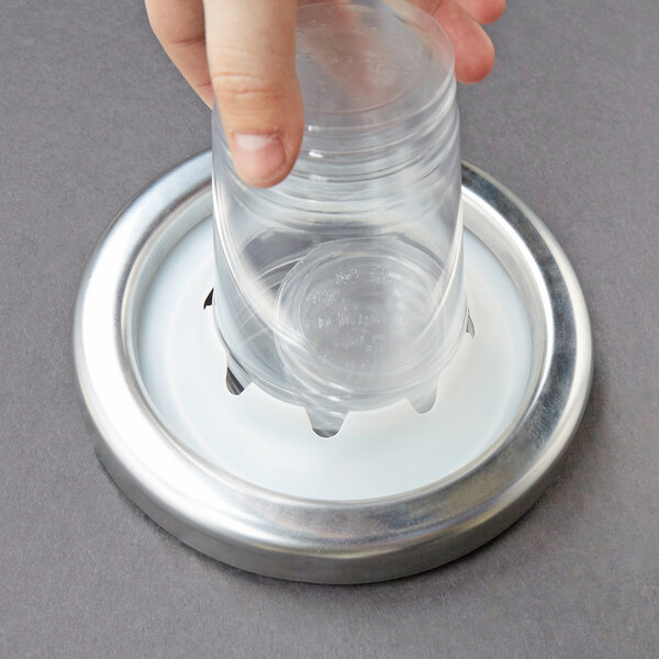 A hand using a Carlisle extra large cup dispenser gasket to hold a plastic cup.