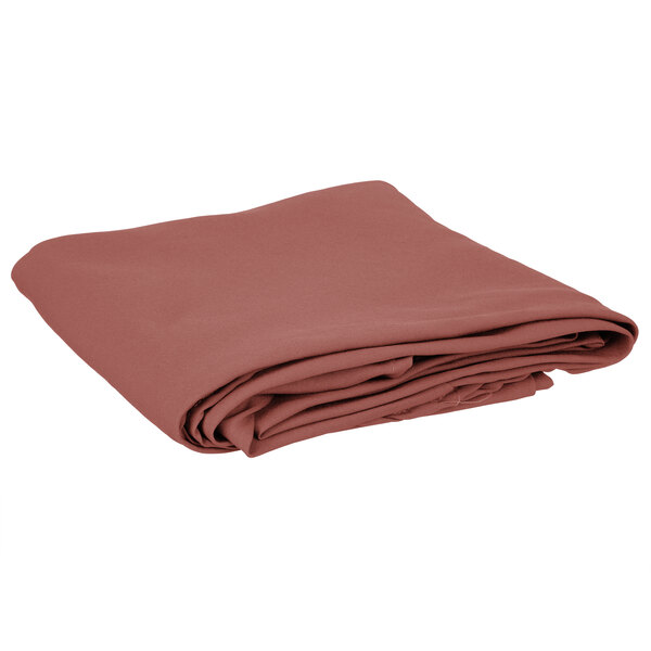 A folded mauve Intedge round cloth table cover.