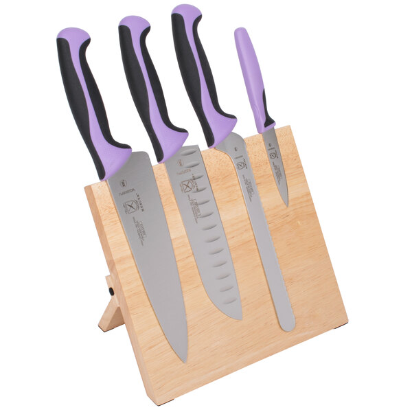 A set of Mercer Culinary Millennia® knives with purple handles on a wooden board.