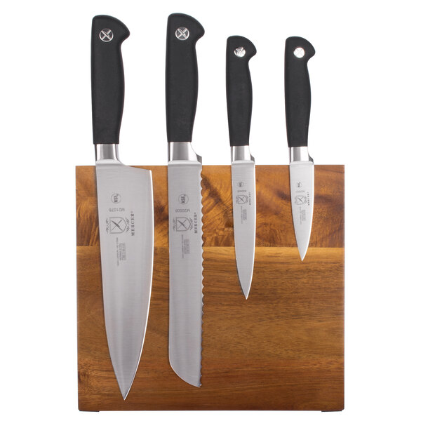 Three Mercer Culinary knives on a Genesis acacia magnetic cutting board.