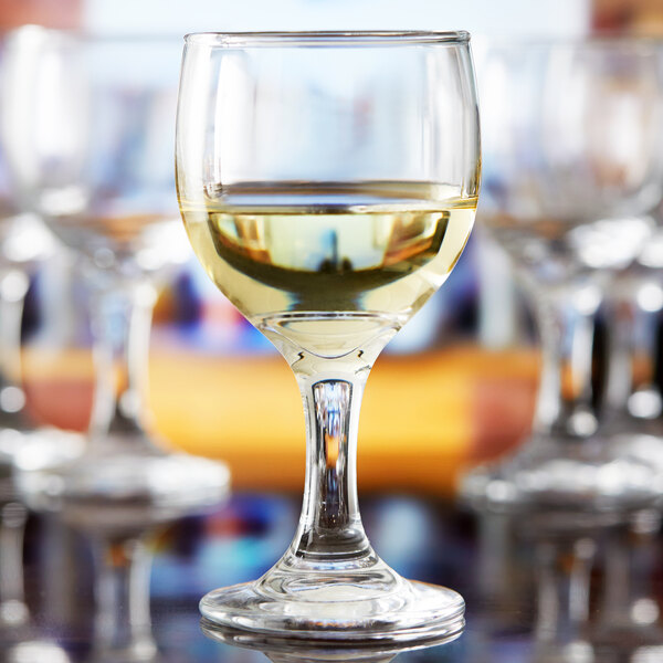 An Anchor Hocking Excellency wine glass filled with white wine on a table.
