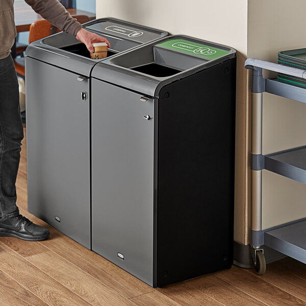 A man standing next to a Rubbermaid Stenni grey recycling container.