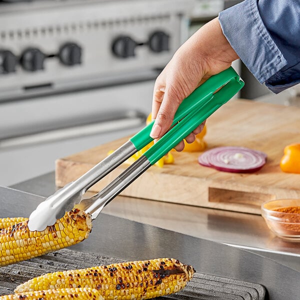 A hand using Vollrath Jacob's Pride tongs to grill corn.
