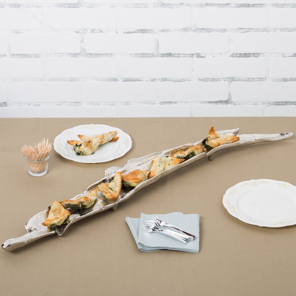 A nickel branch-shaped tray with food on a table.