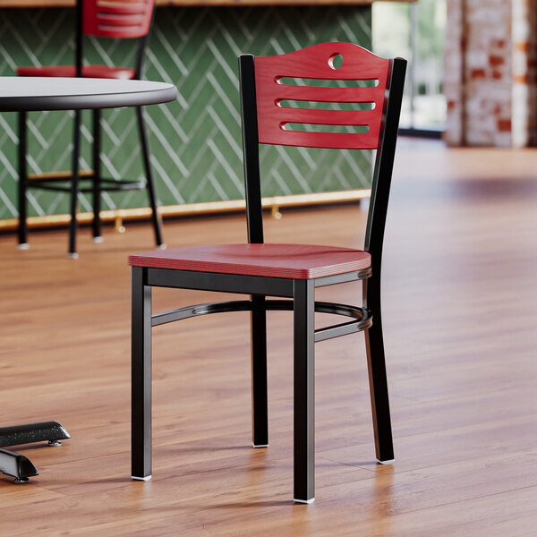 A Lancaster Table & Seating black side chair with a mahogany seat and back on a table in a restaurant dining area.