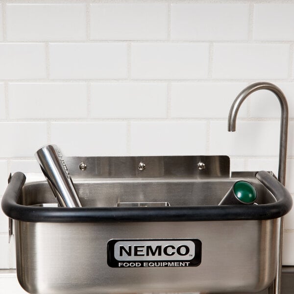 A Nemco stainless steel ice cream dipper well with a metal bowl and faucet.