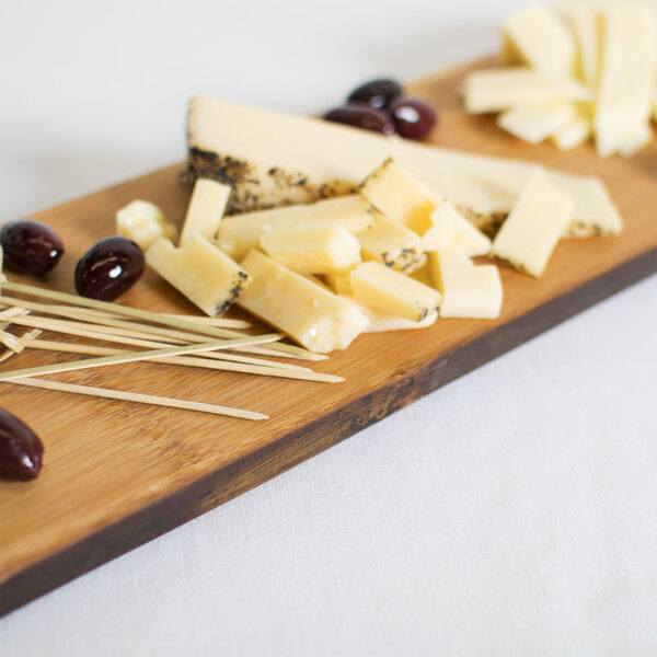 An American Metalcraft carbonized bamboo serving board with cheese and olives on a table.