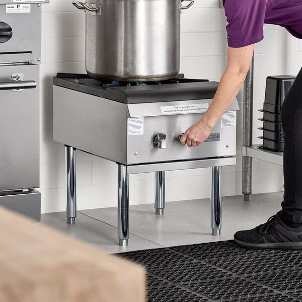 A commercial natural gas stock pot range with a large stainless steel pot on top.