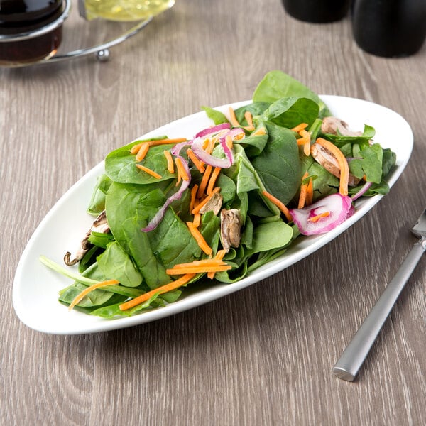 A plate of salad with spinach, carrots, and onions on a 10 Strawberry Street white oval porcelain plate.