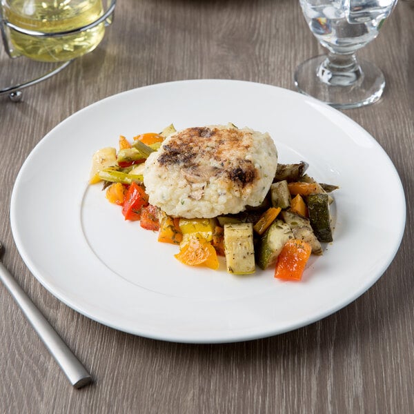 A 10 Strawberry Street white porcelain dinner plate with a piece of fish, carrots, and vegetables on it.