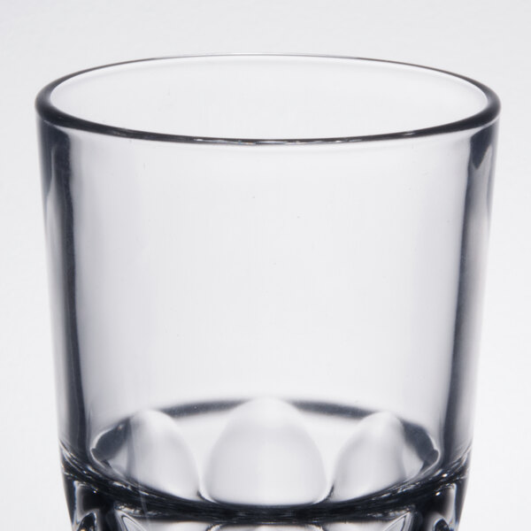 A clear Arcoroc stackable beverage glass with three small holes in the bottom.
