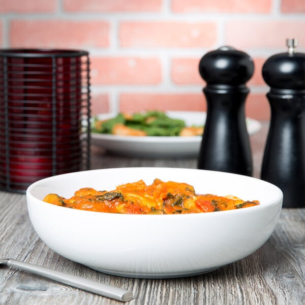 A bowl of pasta with a salt and pepper shaker on a table.