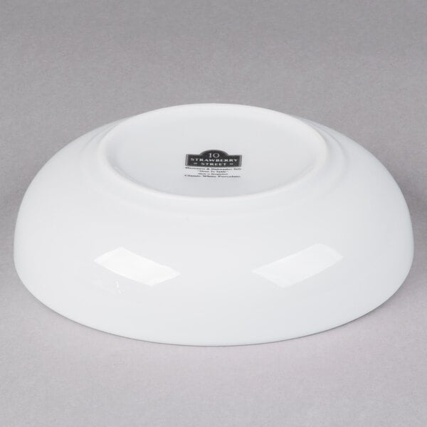 A white 10 Strawberry Street porcelain pasta bowl on a gray surface.
