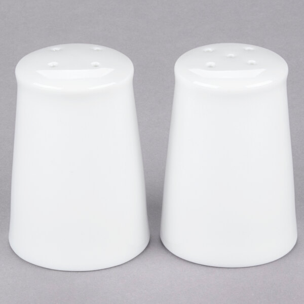 A close-up of two white 10 Strawberry Street salt and pepper shakers.