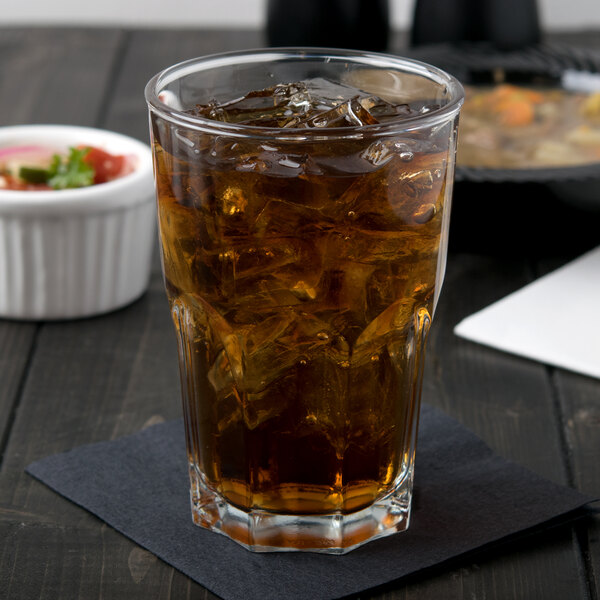 A glass of ice tea with ice on a table.