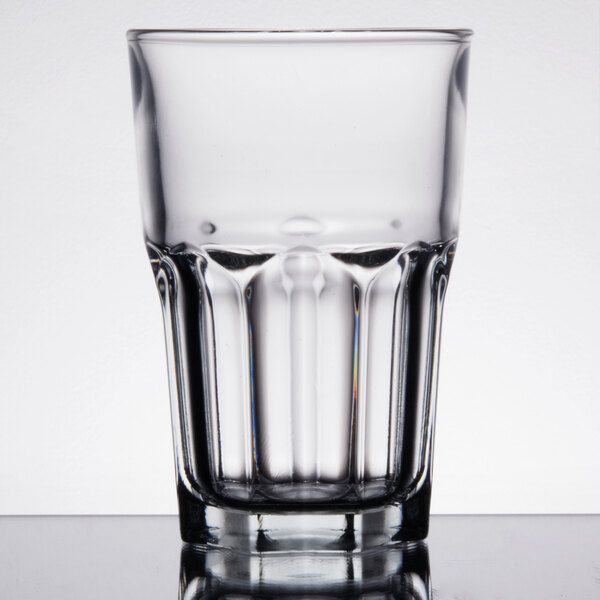 An Arcoroc stackable cooler glass filled with a clear liquid on a white background.