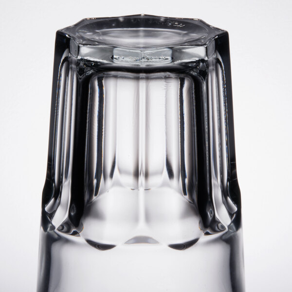 An Arcoroc stackable cooler glass with a black rim on a table.