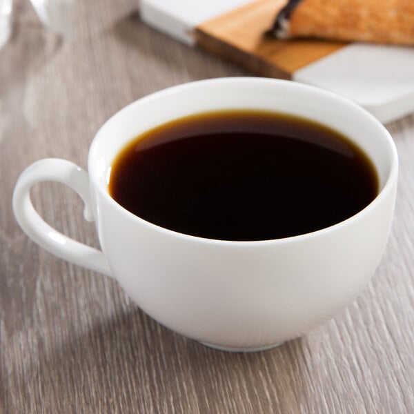 A white porcelain 10 Strawberry Street Ricard coffee cup filled with coffee on a table.