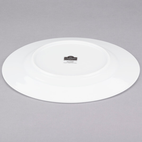 A white 10 Strawberry Street porcelain dinner plate with a black rim on a gray background.