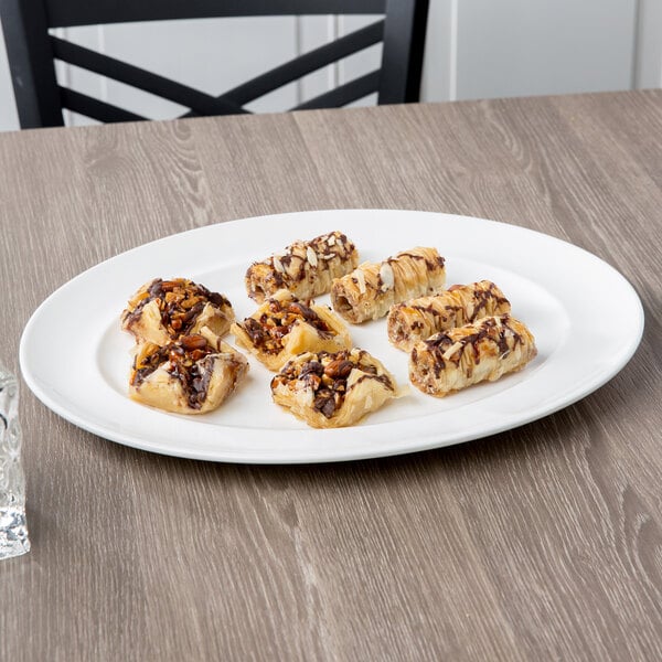 A 10 Strawberry Street white porcelain platter with a plate of pastries on a table.