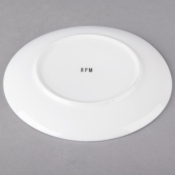 A white round porcelain bread and butter plate with black text that says "Ricard" in the center.