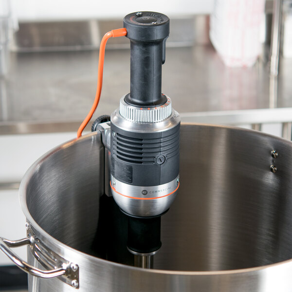 A KitchenAid immersion blender with a cord mixing in a pot.