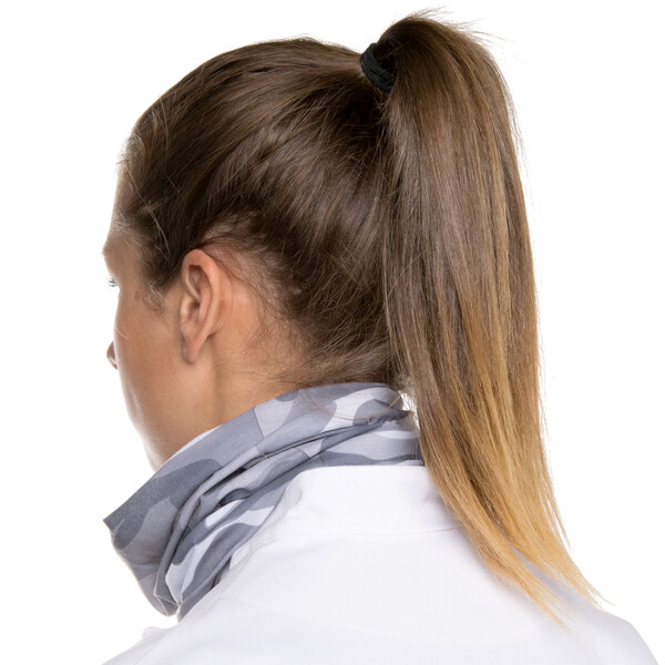 A woman wearing a Headsweats camo headband on her neck with her hair in a ponytail.