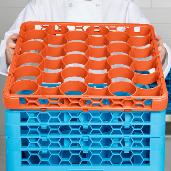 A woman holding a Carlisle orange plastic rack with blue and orange cups.