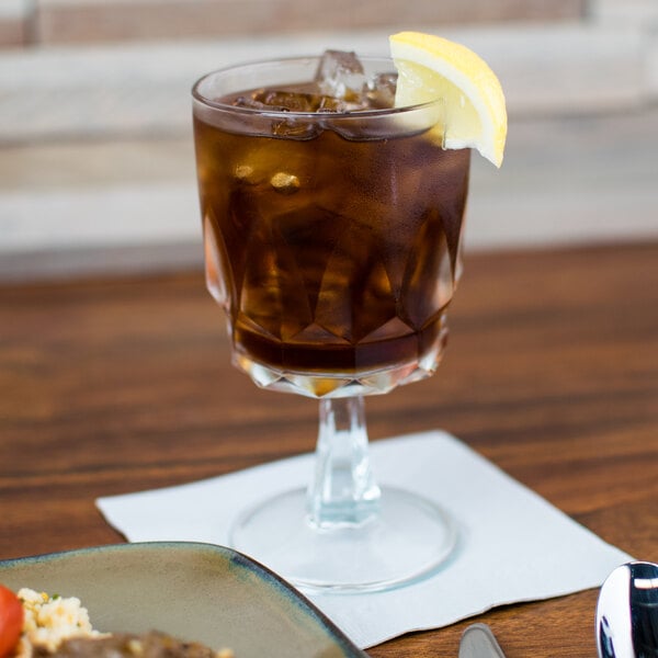 An Arcoroc Artic goblet filled with brown liquid on a table.