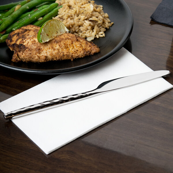 A plate of food with a knife on it, including rice, chicken and green beans.