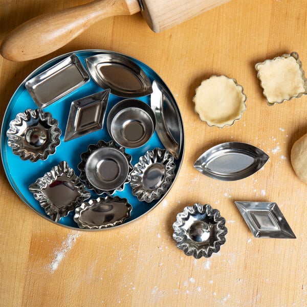 A blue bowl filled with Fox Run metal molds next to a rolling pin.