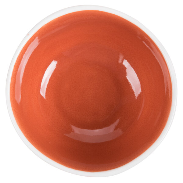A close up of an orange porcelain bowl with a red rim.