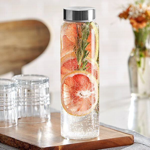 A Libbey glass water bottle with lemon and rosemary slices on a wooden counter.