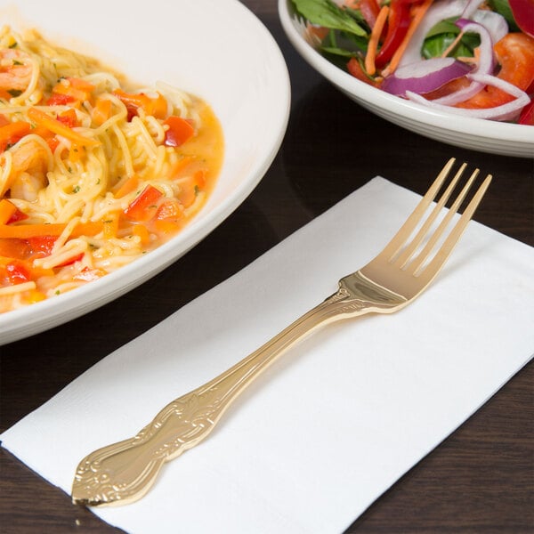 A 10 Strawberry Street Crown Royal gold plated stainless steel dinner fork next to a bowl of noodles.