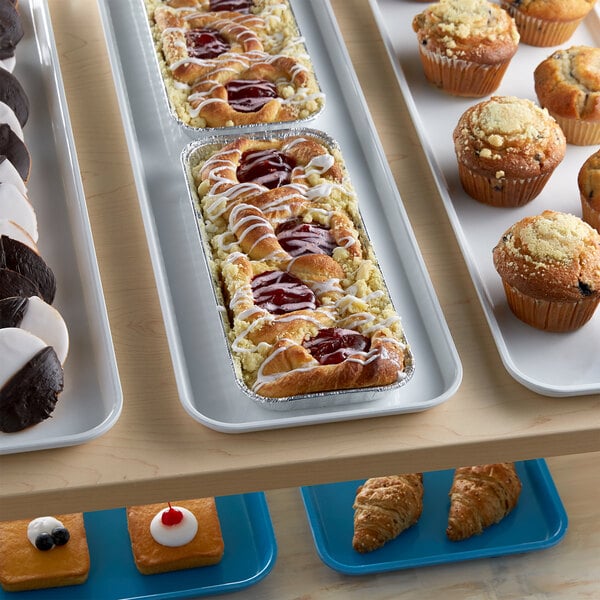 A white Cambro market tray of pastries and muffins on a table.