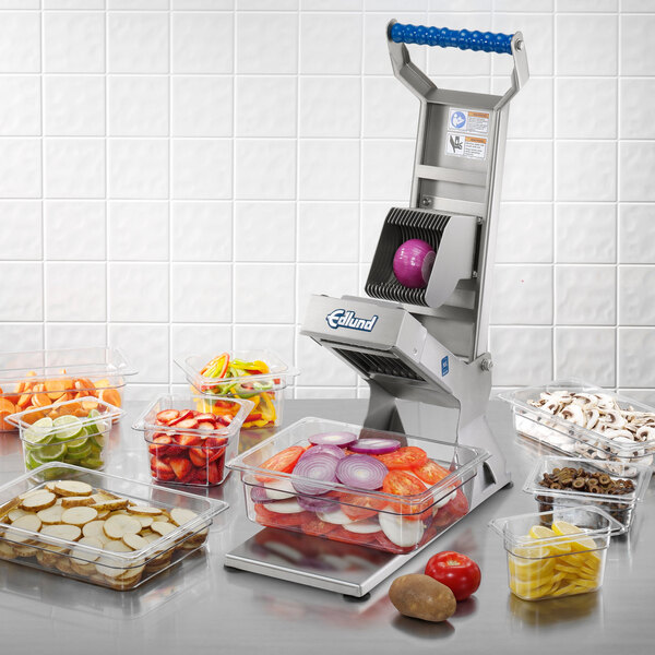 An Edlund ARC! 1/4" Pusher Head assembly on a food processor with containers of sliced strawberries and lemon slices.