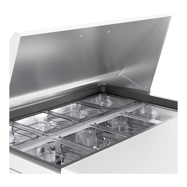 A True refrigerated sandwich prep table with a stainless steel lid open over a container.