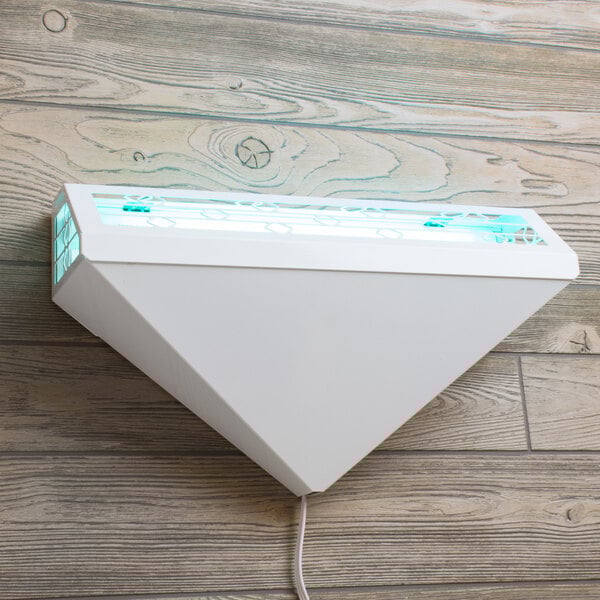 A white triangular light fixture on a wood surface.