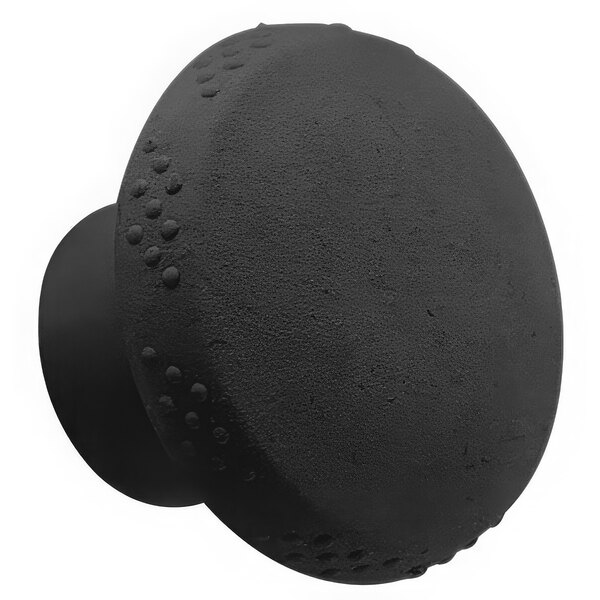A close-up of a black round knob with holes in it.